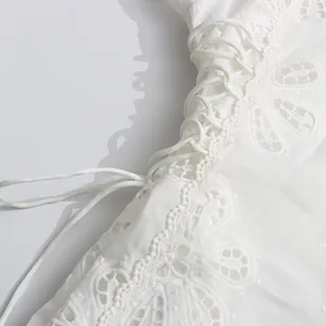Detalle de encaje calado 3D y cordones en un vestido blanco de estilo palaciego retro.
