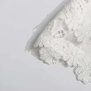 Primer plano detallado del intrincado encaje floral blanco en 3D de una manga de vestido retro