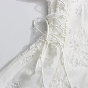Primer plano detallado del intrincado encaje floral blanco y el cordón lateral del vestido