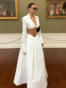 Elegant white 2-piece set featuring V-neck cropped top and long flowing skirt in museum setting.