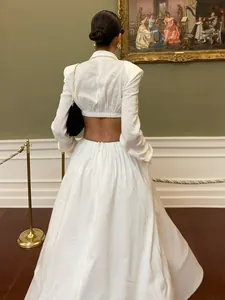 Elegant white two-piece set featuring cropped long sleeve top and full maxi skirt