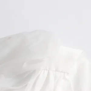 Detailed close-up showing white mesh fabric and pleats on an elegant V-neck dress.