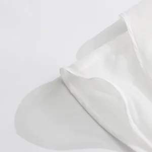 Close-up of fine stitching and mesh texture on a white summer gauze dress.