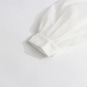 Close-up of white mesh dress sleeve featuring a delicate solid white stitched cuff