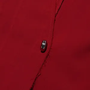 Close-up of silver bean-shaped button on a red coat with frayed edge detail.
