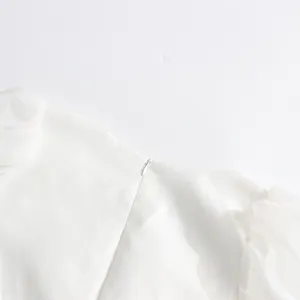 Close-up detail showing the invisible back zipper and puffy mesh sleeves of this white dress