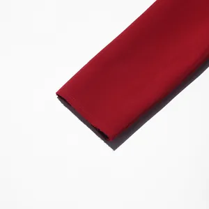 Detail shot of deep red coat sleeve with raw edge finish on white background.
