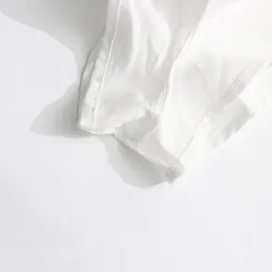 Close-up showing the delicate overlock stitching and mesh fabric texture of a white dress