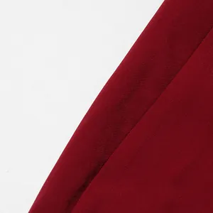 Close-up of the burgundy woven fabric texture on the elegant long shawl-style coat
