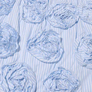 Close-up of French vintage 3D flower appliqué on blue and white striped fabric texture