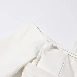 Detalle de un blazer blanco de estilo francés con hombros caídos y diseño de malla plisada