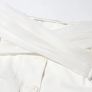 Detalle de chaqueta blanca con hombros descubiertos y elegante diseño cruzado.