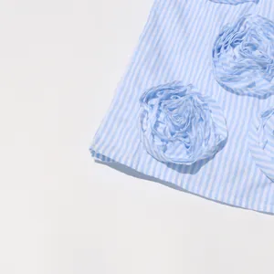 Close-up detail of a blue and white striped dress featuring 3D fabric flower appliqués