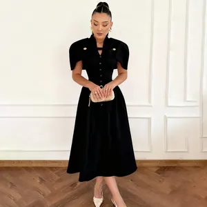 Elegantes schwarzes Vintage-Kleid mit Stehkragen und Cape-Design an einem Modell im Raum.