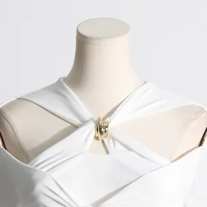Dettaglio di abito in maglia minimalista con scollatura a goccia e fibbia dorata