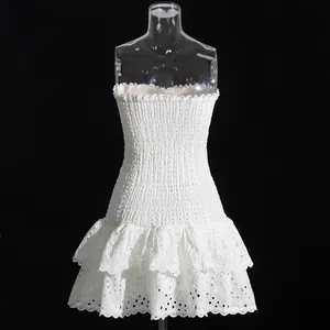 Detail view of white eyelet lace tiered ruffle hem and smocked bodice of a mini dress.