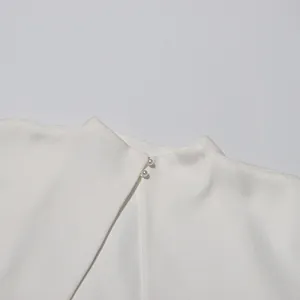 Detailansicht eines eleganten weißen Kleides mit zarten Perlenknöpfen am Rückenausschnitt