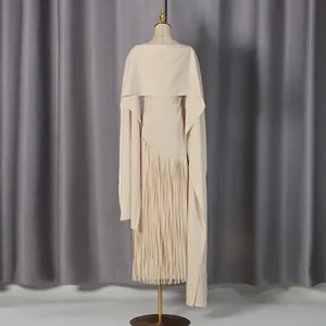 Detailed macro view of elegant beige slim-fit dress featuring a chic cape and long fringe hem