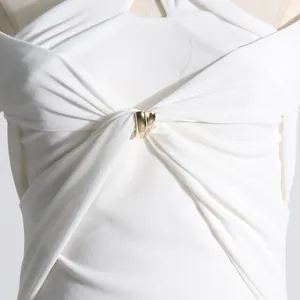 Primo piano dell'elegante nodo con fibbia dorata su un abito bianco in stile francese.