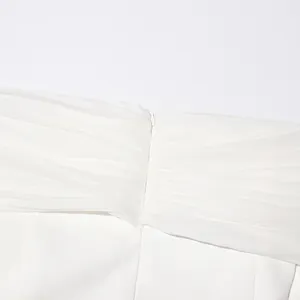 Vista detallada del elegante tejido de malla blanca en un blazer con hombros descubiertos