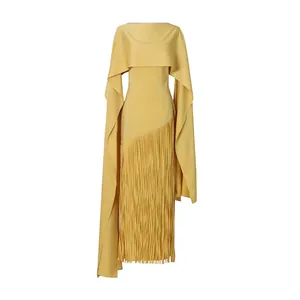 Detail of yellow cape dress featuring long swaying fringe hem and slim fit silhouette.