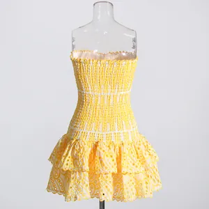 Detail of yellow smocked dress featuring delicate eyelet embroidery and tiered ruffles