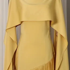 Close-up of yellow cape dress detail featuring an elegant pleated hem and smooth satin texture.