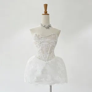 Detailed view of a white lace embroidered strapless mini dress on a mannequin
