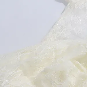 Nahaufnahme des aufwendigen Blumenmusters und der Pailletten des weißen Spitzenkleids