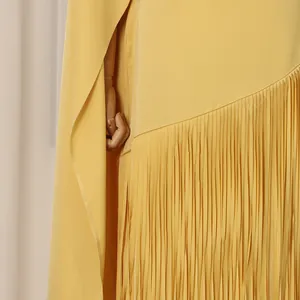Detail shot of yellow cape dress showing pleated fringe hem and fabric texture.