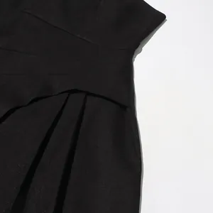 Nahaufnahme eines eleganten schwarzen Trägerkleides mit Plissee-Details und Stoffstruktur.