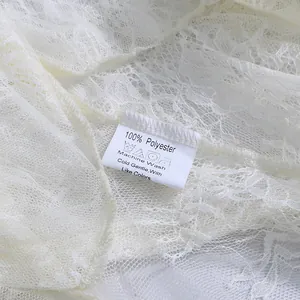 Nahaufnahme des Pflegeetiketts eines weißen Spitzenkleides aus 100 % Polyester Material
