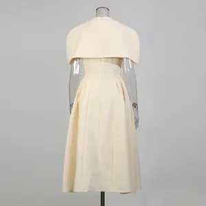 Rückansicht eines eleganten cremefarbenen Midikleides mit schickem Cape und Faltenrock.
