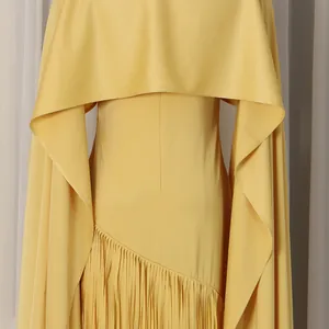 Detailed view of a yellow slim-fit dress featuring a cape design and fringe tassel hemline.