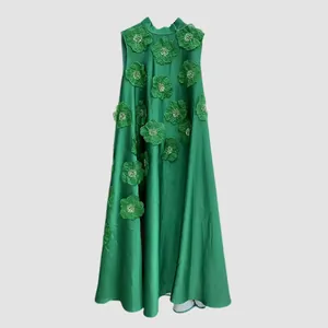 Détail d'une luxueuse robe maxi verte sans manches avec des appliqués floraux en 3D