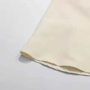 Detaillierte Makroansicht der professionellen Saumnaht an diesem eleganten cremefarbenen Kleid