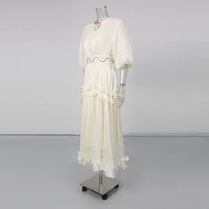 Side view of an elegant French white maxi dress with puff sleeves and ruffles on a mannequin.