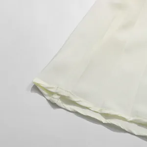 Detailaufnahme des plissierten Saums und der feinen Nähte eines eleganten cremefarbenen Kleides