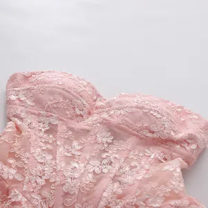 Detail view showing intricate white floral lace embroidery on a pink strapless dress.