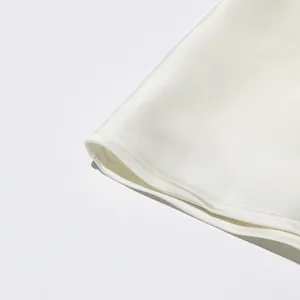 Détail du tissu satiné lisse et des coutures d'ourlet soignées sur la robe blanche