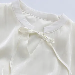 Detail of elegant white dress neckline featuring a delicate tie-up bow and satin texture.