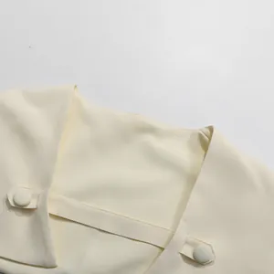 Detaillierte Makroaufnahme des eleganten Stehkragens mit Knöpfen am cremefarbenen Kleid