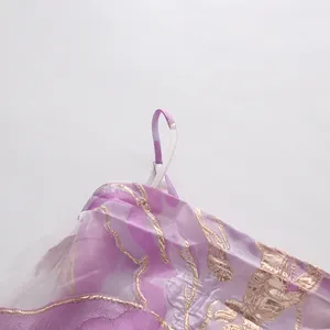 Dettaglio del vestito viola da resort con elegante motivo floreale dorato e raffinato.