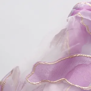 Dettaglio ravvicinato del tessuto organza viola con ricami dorati su abito a fiori
