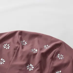Close-up of rhinestone floral patterns on a mauve French style palace dress fabric.