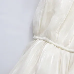 Close-up of white shimmery pleated fabric and gathered waist detail on an elegant dress.