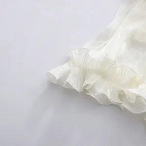 Detail view of white ruffled hem with elegant pleated shimmer texture and delicate finish