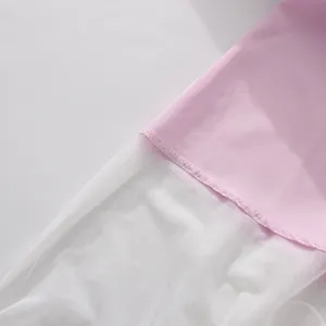 Primo piano del tessuto rosa e del bordo in rete bianca di un abito estivo.