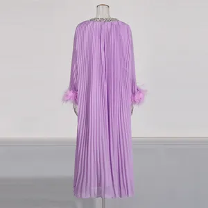 Detail view of purple pleated maxi dress featuring ostrich feather cuffs and rhinestone collar.