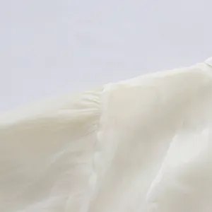 Close-up of puff sleeve shoulder seam and gathered fabric on an elegant white dress.